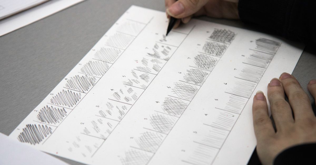 Close-up photo of hands using a pen to practice shading techniques on paper.